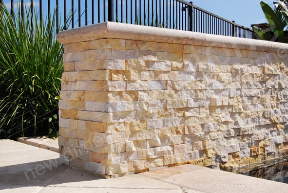 Norstone Finger Joint Corner Units shown in Ivory covering two outside corners on an exterior landscape wall with Travertine Cap